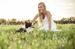 Beautiful blonde woman playing and stroking her loyal border collie