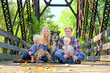 Family of Four People and Dog Sitting On Bridge in Autumn